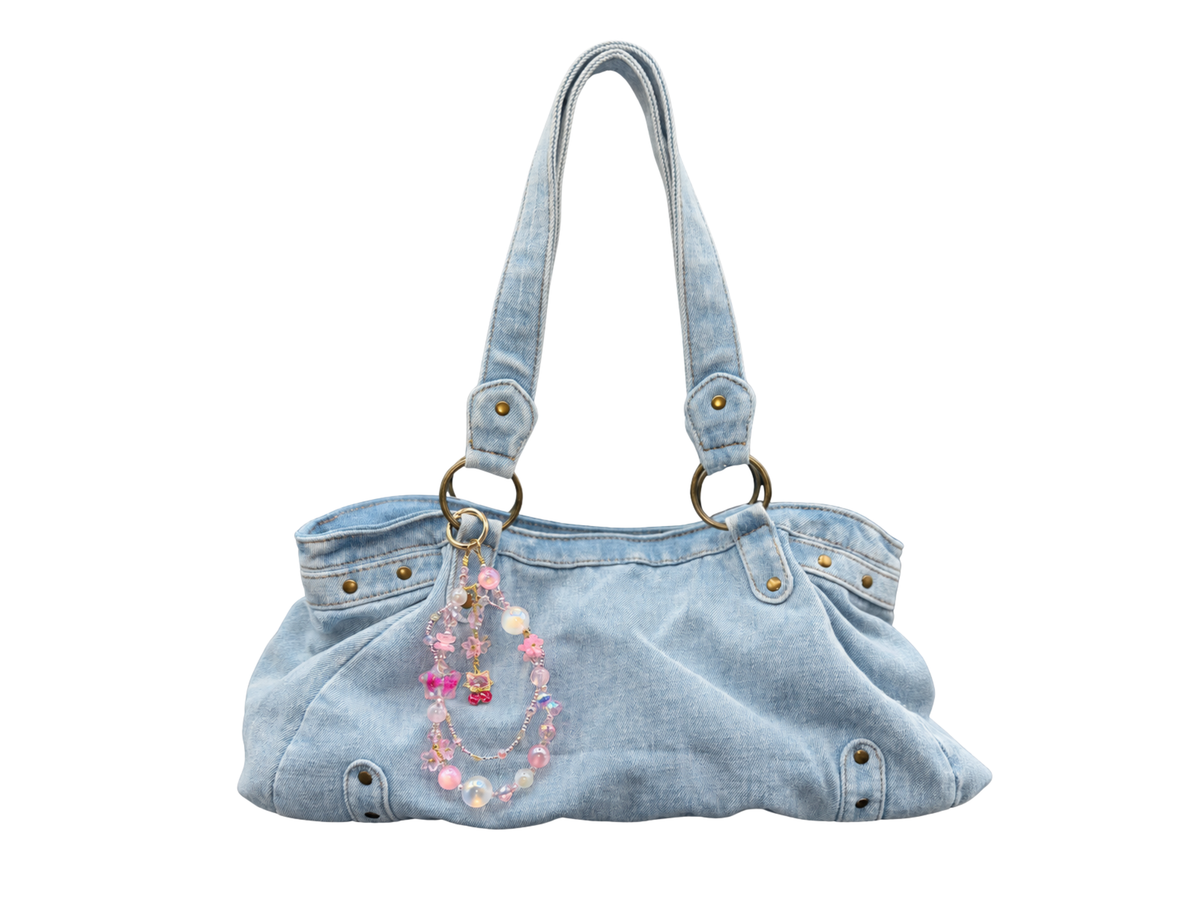 Bracelet Chérie Bloomeliya rose bonbon et perles irisées, accroché à un sac à main