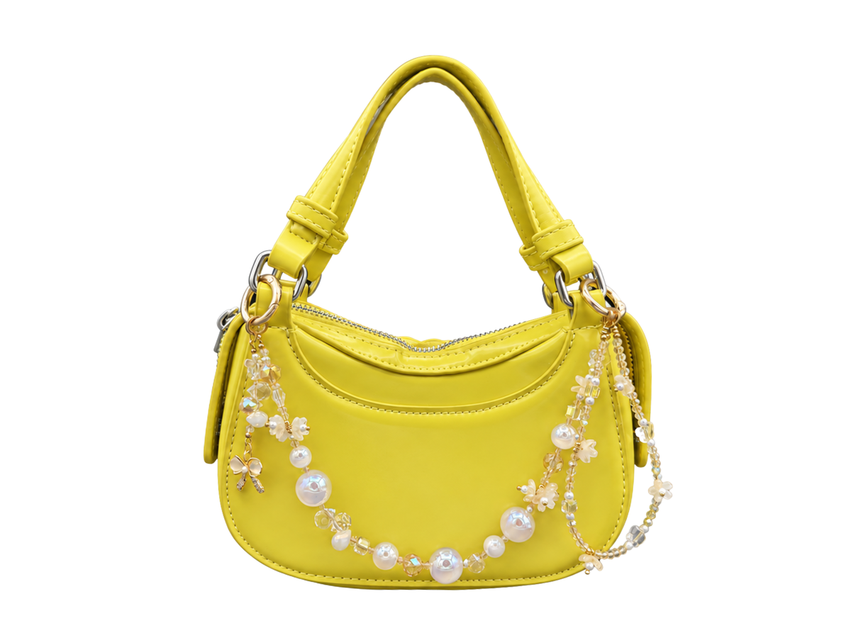 Bracelet Fleur de lait Bloomeliya ivoire, perles nacrées et nœud doré, accroché à un sac à main